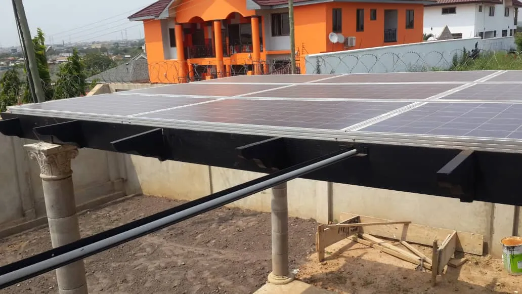 Ground-mounted solar array beside a family home