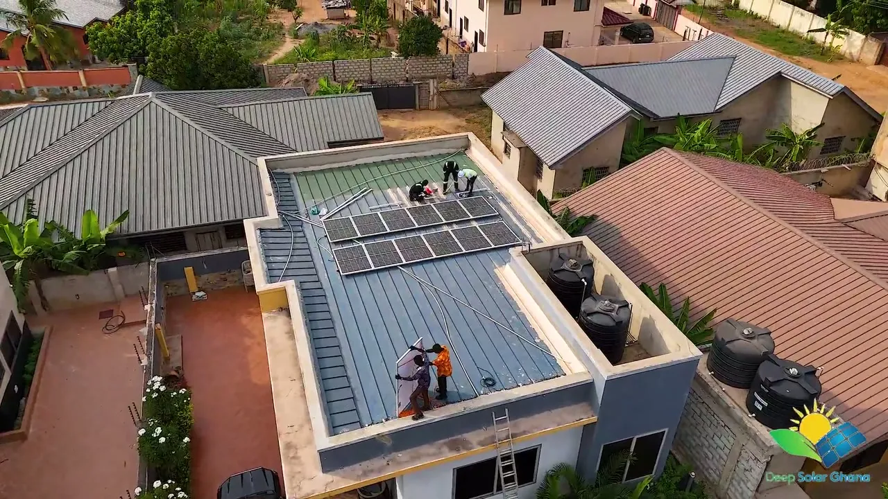 Deep Solar Ghana team installing solar panels on a flat rooftop in Accra, seen from a drone